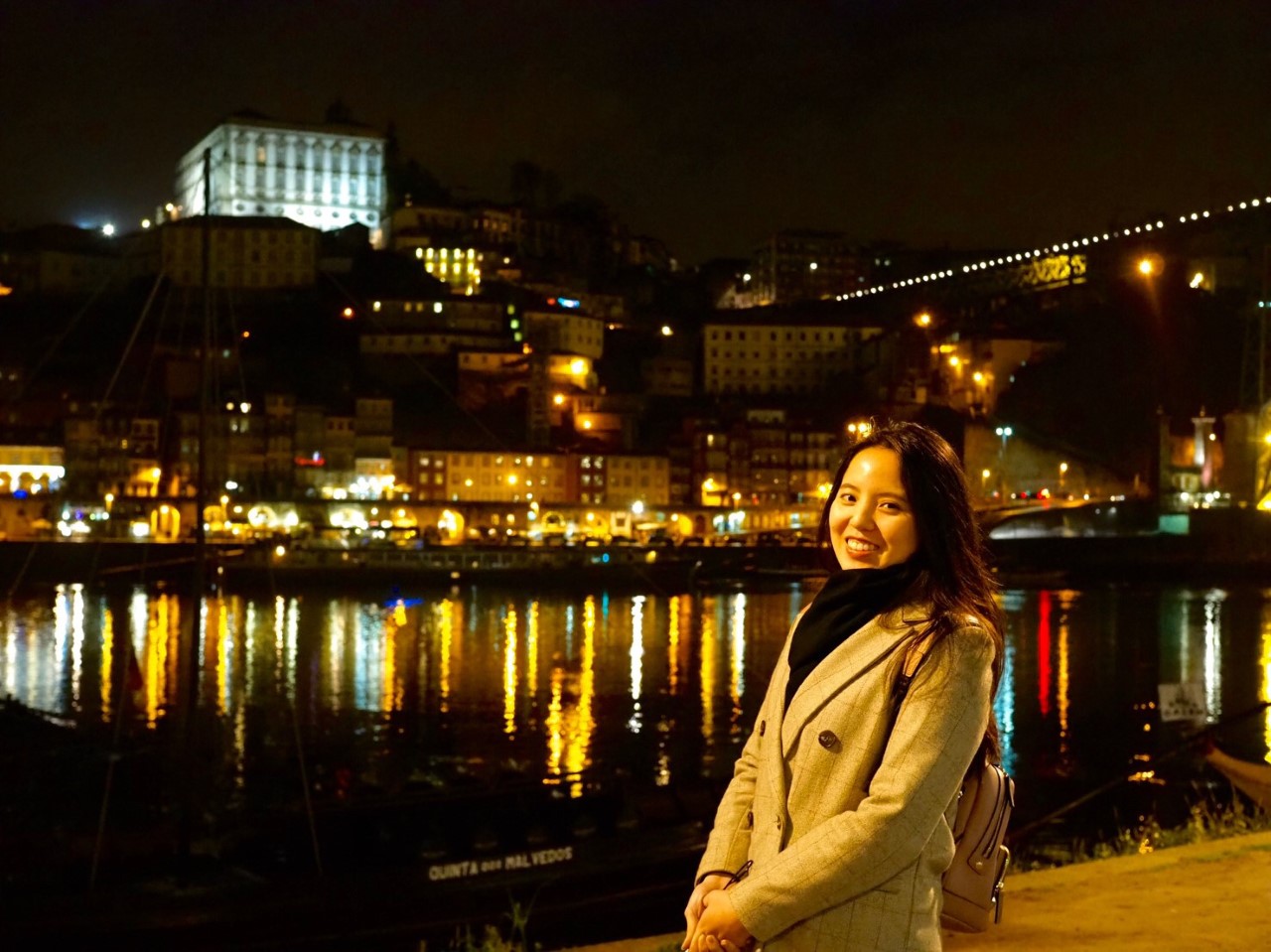Estelle with at night time with building lights reflecting off of the river in the background